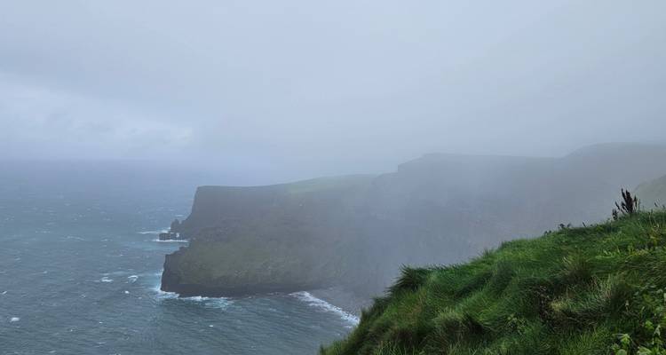 Falaises brumeuses surplombant une mer agitée.