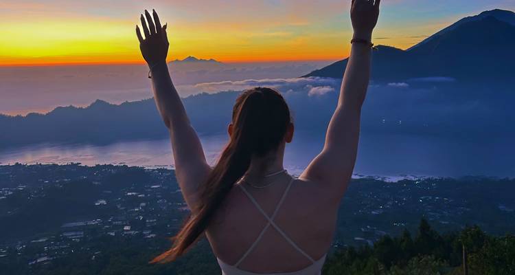 Silhouette d'une personne contre un lever de soleil vibrant au-dessus des montagnes.