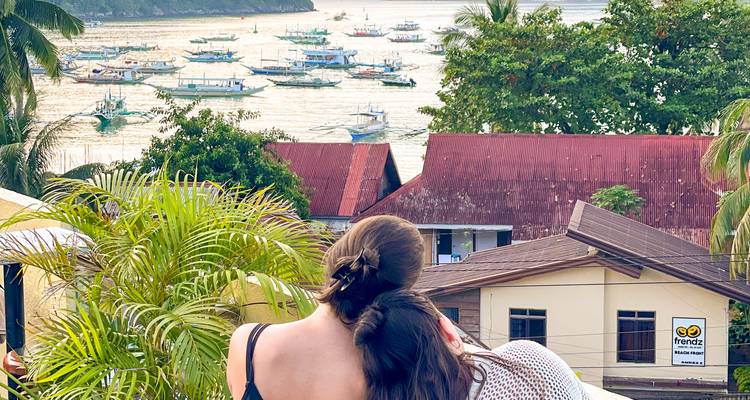 Deux personnes surplombant une baie avec de nombreux bateaux amarrés.