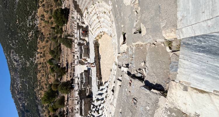Amphithéâtre antique avec des gens qui explorent le site.