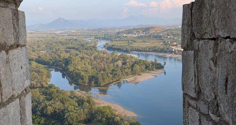 Vue panoramique d'une rivière avec une végétation luxuriante depuis une fenêtre de forteresse.
