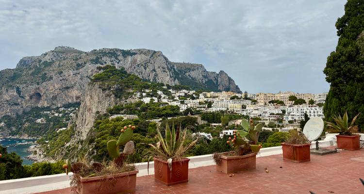 Village à flanc de colline avec des bâtiments blancs et un décor de montagne en arrière-plan.