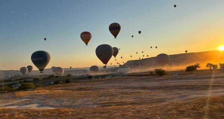 Montgolfières s'élevant au-dessus d'un paysage rocheux au lever du soleil.