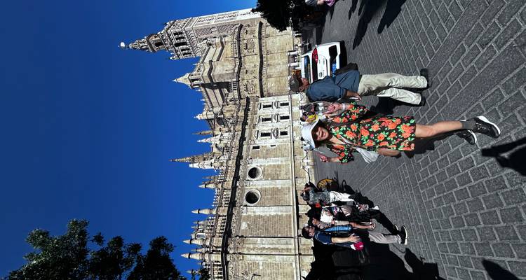 Mensen die poseren voor een historisch gebouwencomplex met een hoge toren.