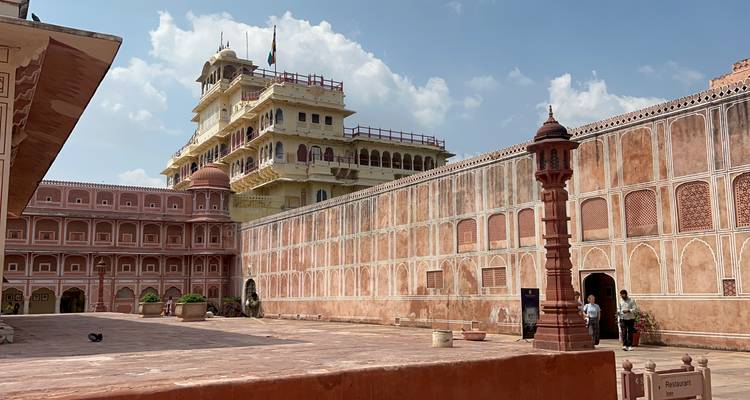 Innenhof eines historischen rosa und gelben Palastes mit kunstvoller Architektur in Jaipur, bekannt für seine Paläste und Festungen.