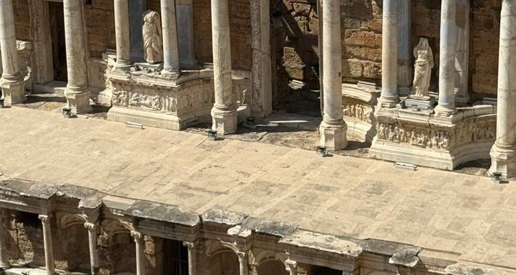 An ancient stone theater with columns and statues, capturing classical architecture.