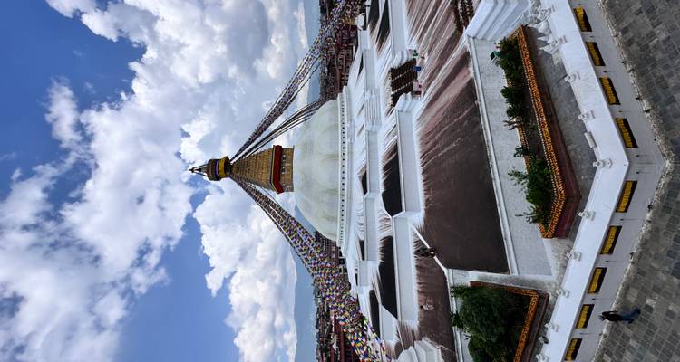 A wide view of Baudhanath Stupa under a cloudy sky.