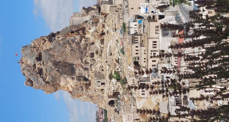 A large rock formation with dwellings at its base.