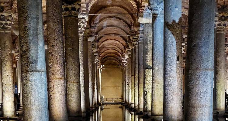 Una serie de columnas reflejándose en el agua dentro de una estructura antigua.