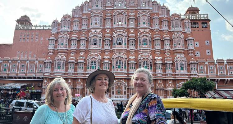 Drie vrouwen poseren voor een historisch gebouw.