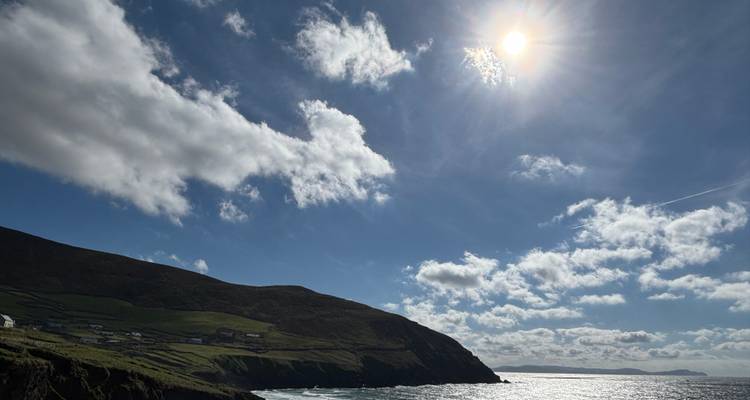 Paysage côtier avec une vue sur la mer et le soleil dans le ciel.