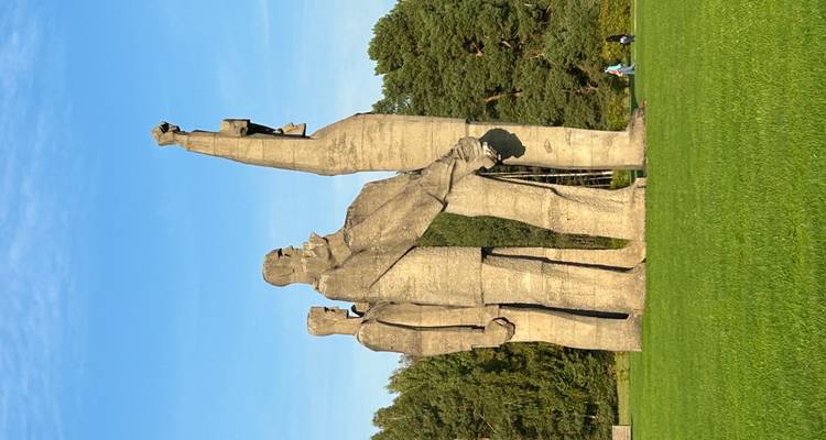 Sculpture de trois grandes figures dans un champ herbeux.