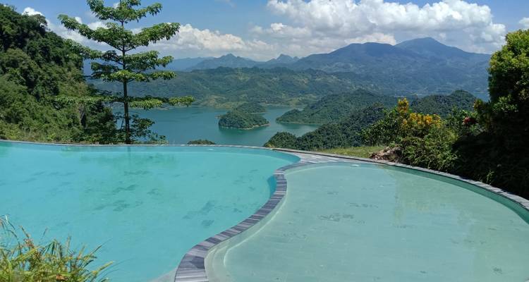 Infinity pool overlooking a picturesque landscape with mountains and a lake.