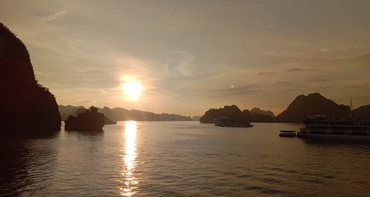 Sunset over a bay with cruise boats visible on the water.