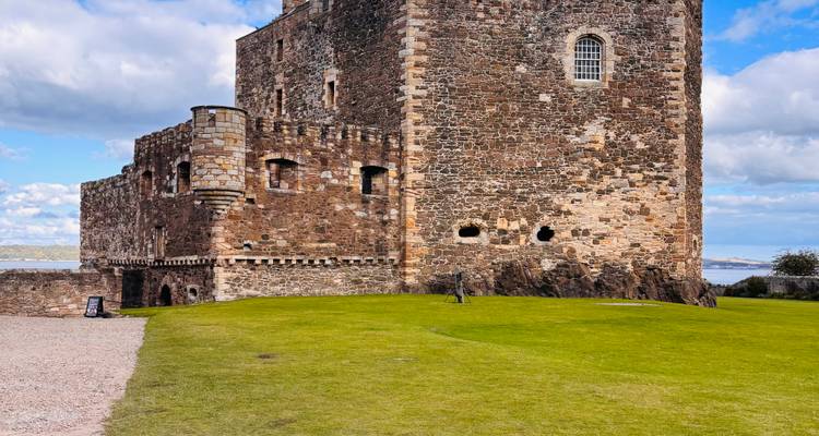 Extérieur d'un château historique en pierre avec une herbe luxuriante.