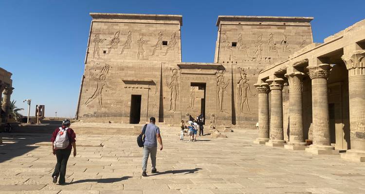 Ancien temple de pierre avec des touristes qui marchent vers lui.