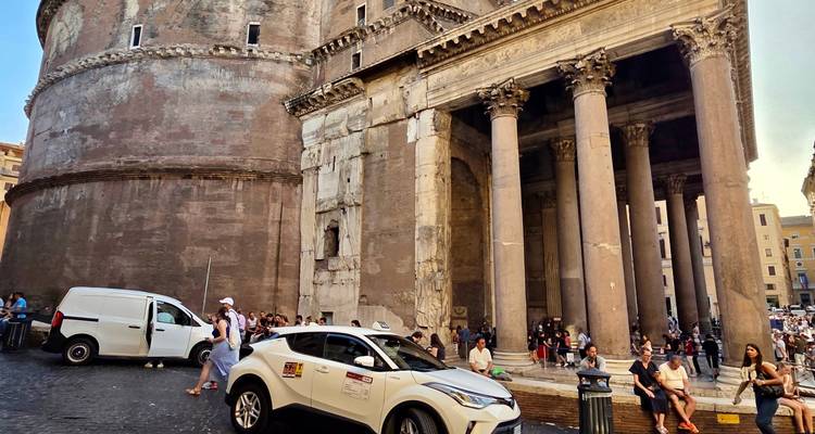 Le Panthéon à Rome avec des voitures garées et des gens autour.