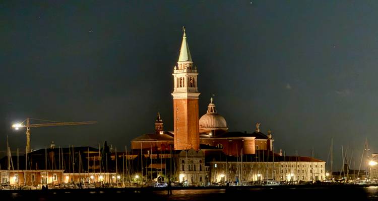 Vue nocturne d'une église éclairée avec un haut clocher à Venise.