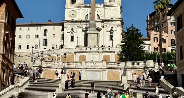 Foule aux escaliers de la Trinité-des-Monts à Rome, sous un ciel dégagé.