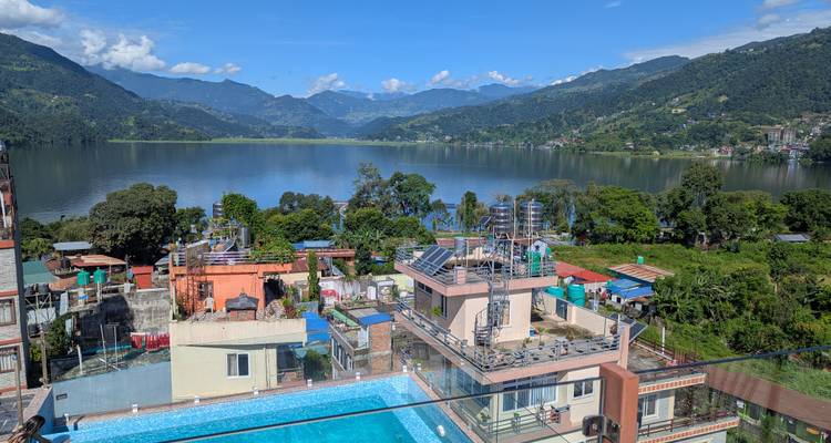Vue panoramique sur un lac et des montagnes avec une piscine au premier plan.