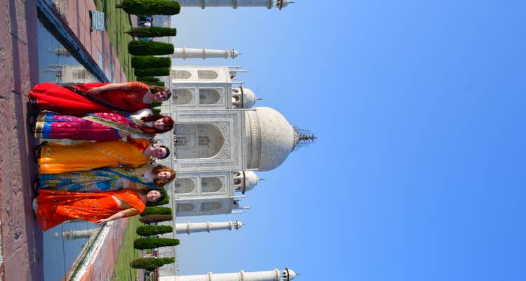 Cinq femmes en saris colorés posant devant le Taj Mahal.