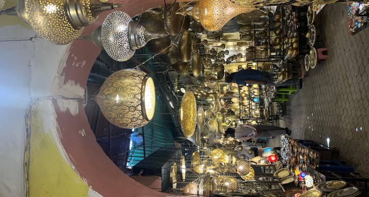 A vibrant market with hanging lanterns and shoppers walking through.