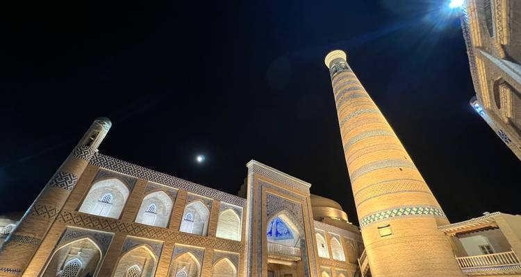 Vue nocturne de bâtiments anciens magnifiquement éclairés avec un croissant de lune.