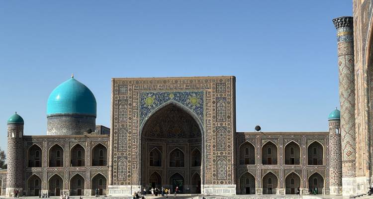 Des personnes explorant un grand bâtiment aux motifs complexes.