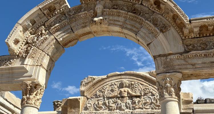 Sculptures complexes sur une arche de pierre ancienne avec un ciel dégagé.
