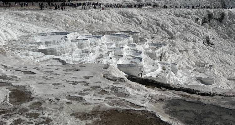 Weiße Travertinterrassen mit Besuchern.