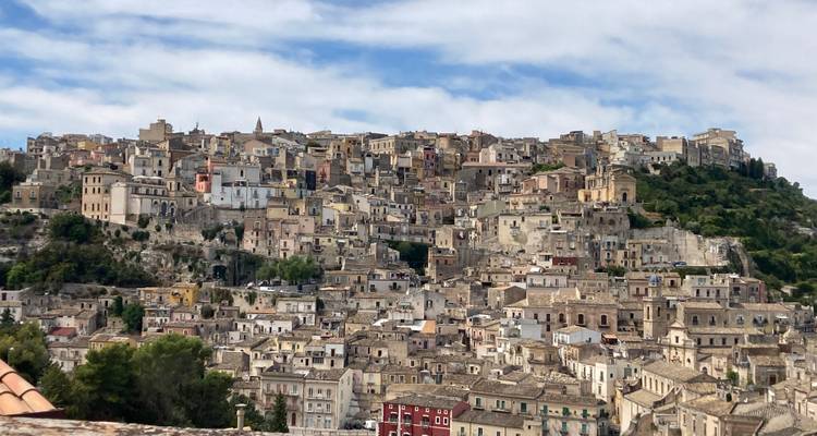Ville historique à flanc de colline avec de nombreux bâtiments en pierre.