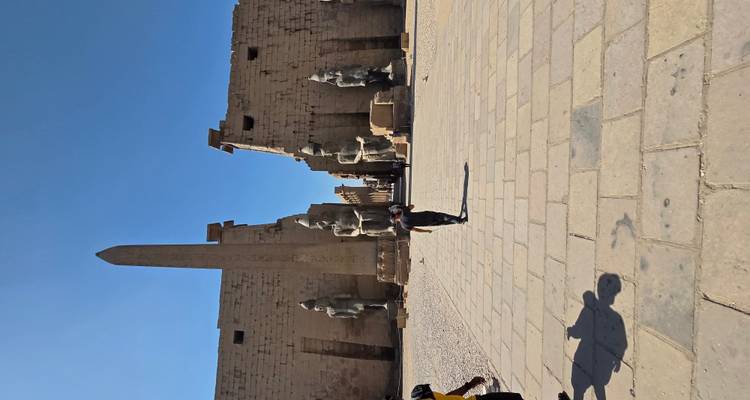 Luxor temple entrance with statues and a person walking.