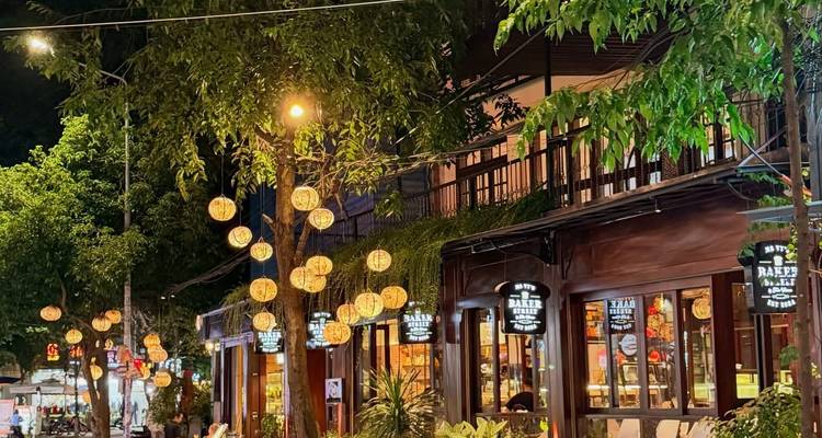 Scène de rue animée avec des lumières et des arbres la nuit.