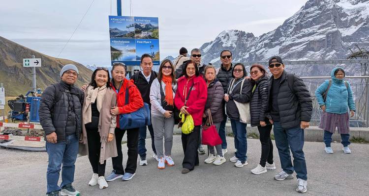 Groupe de personnes debout avec une vue sur des montagnes enneigées.