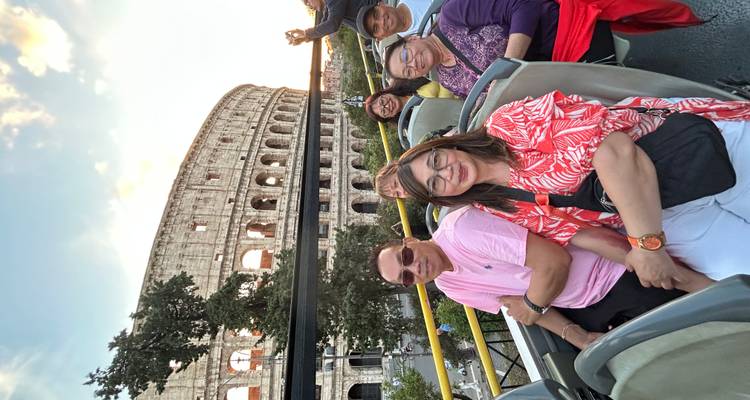 Touristes dans un bus à toit ouvert avec le Colisée en arrière-plan au coucher du soleil.