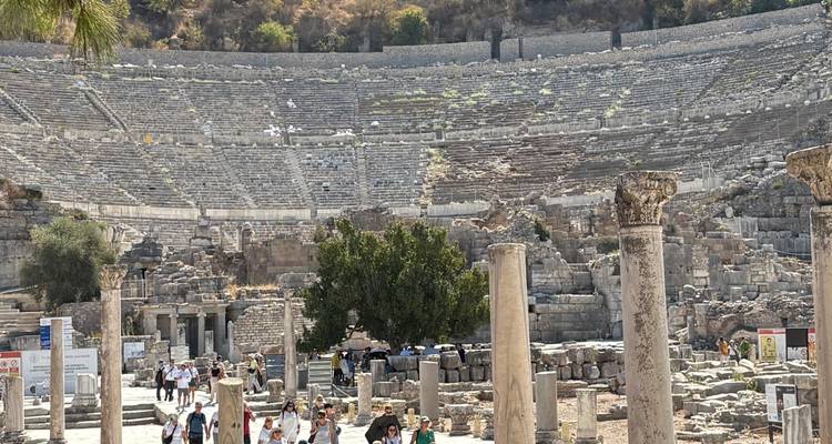 Amphithéâtre antique avec des touristes explorant les ruines.