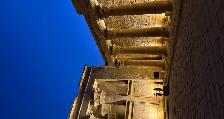 Temple d'Edfou illuminé la nuit avec des colonnes antiques.