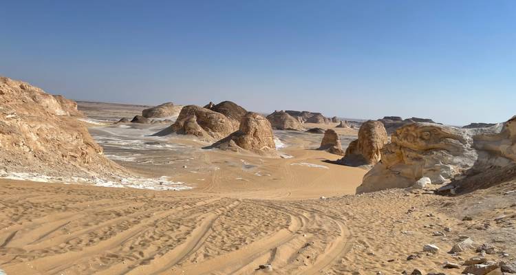 Vue désertique de sable avec formations rocheuses.