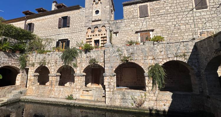 Bâtiment en pierre rustique avec ouvertures voûtées et plantes.
