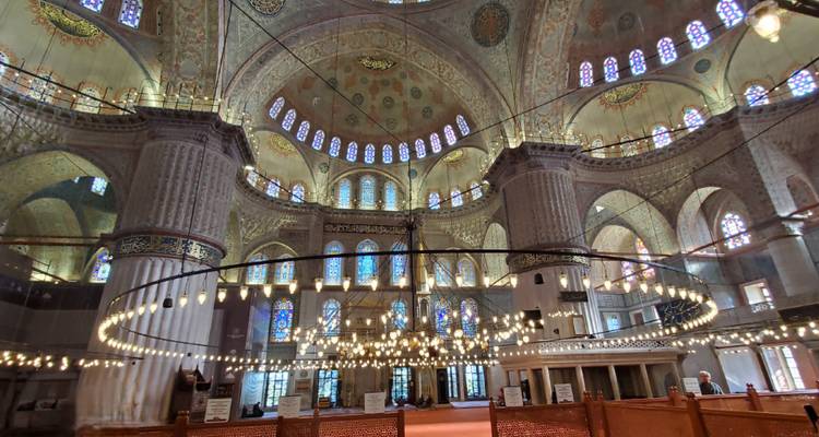 Intricately decorated grand interior with dome and stained glass windows.