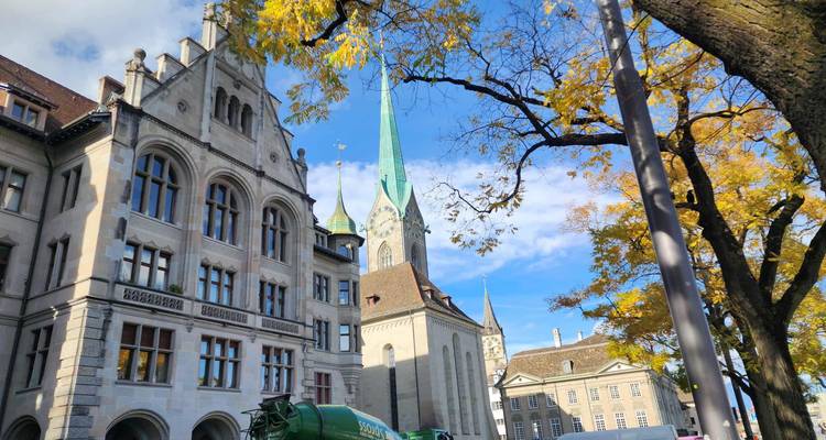 Vue panoramique d'une église avec un clocher, entourée d'arbres au feuillage d'automne.