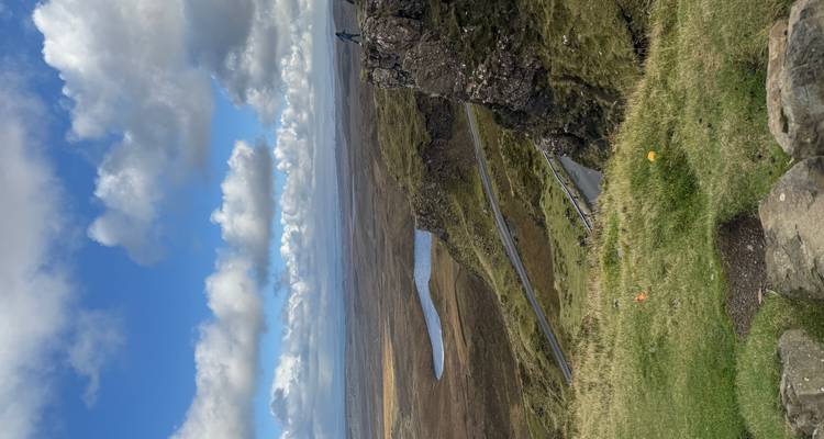 Vaste paysage avec des collines ondulantes et une personne solitaire sur une falaise.
