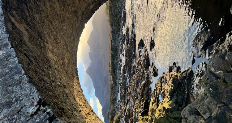 Rivière coulant sous un pont de pierre avec des montagnes en arrière-plan.