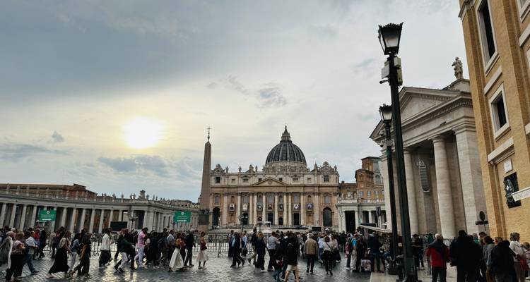 Platz in Rom mit einer großen Basilika und Menschen, die herumlaufen.