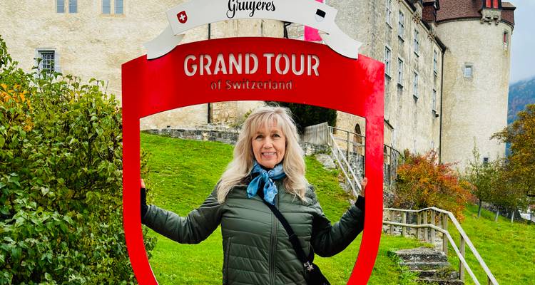 Frau posiert mit 'Grand Tour of Switzerland' Schild.