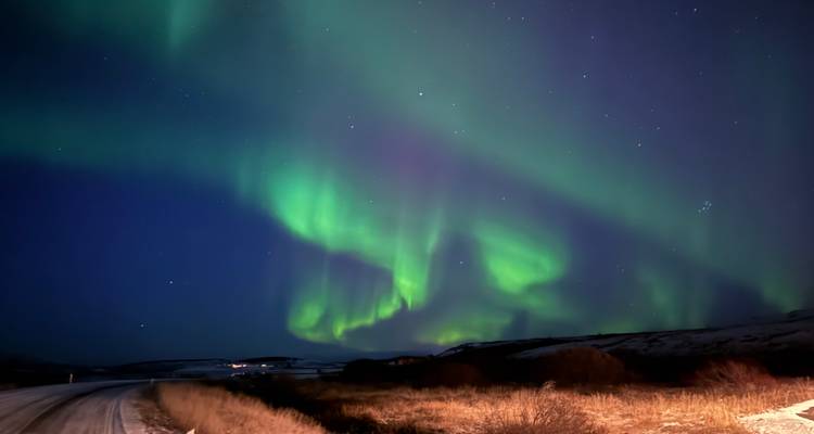 Nordlicht über einer ländlichen Landschaft bei Nacht.