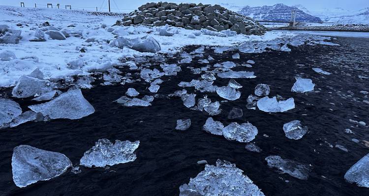 Chunks of ice scattered on a black sand beach.