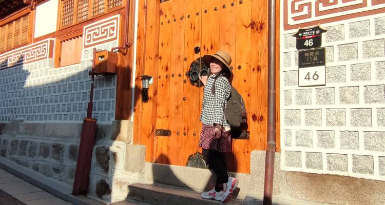 Persoon poseert voor een traditionele houten poort.