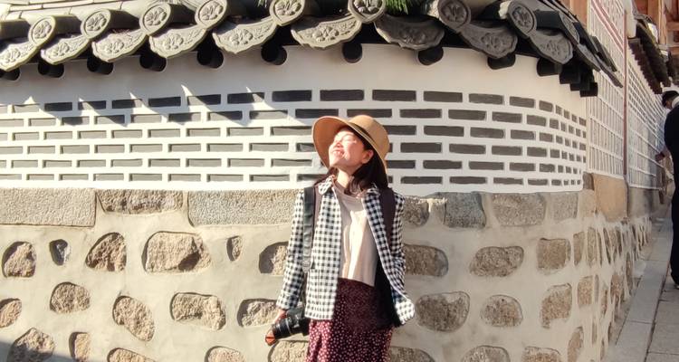 Persoon die van de zon geniet voor een traditioneel Koreaans huis.