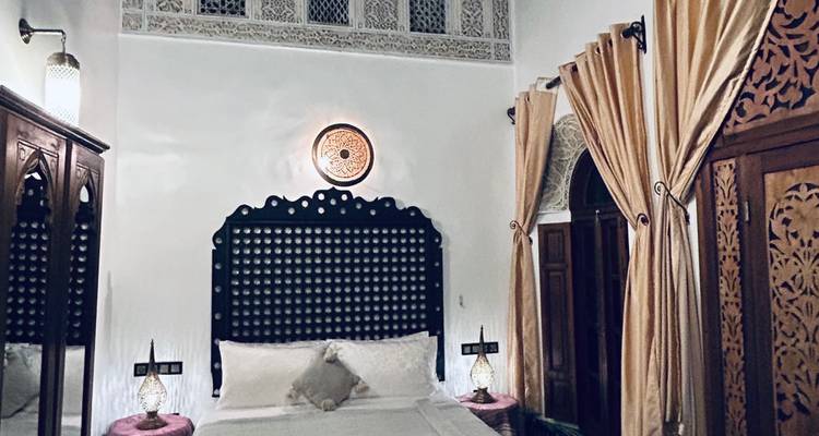 Intricately decorated room interior with a bed and drapes.